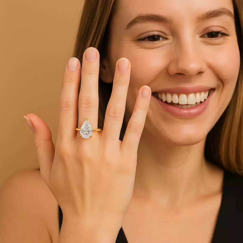 UN1007 (2) Smiling woman wearing 5ct pear cut lab diamond ring in yellow gold – elegant engagement ring lifestyle photo