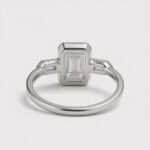 Front view of three-stone engagement ring with emerald cut center diamond and baguette sides in white gold