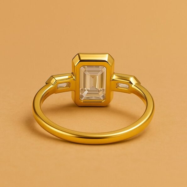 Back view of emerald cut three-stone diamond ring in yellow gold setting on solid background