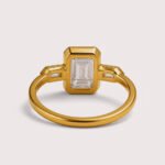Front view of three-stone engagement ring with emerald cut center diamond and baguette sides in white gold