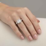 Front view of three-stone engagement ring with emerald cut center diamond and baguette sides in white gold