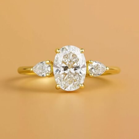 Oval cut lab-grown diamond engagement ring with pear-shaped side stones set in yellow gold, front view.