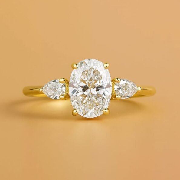 Oval cut lab-grown diamond engagement ring with pear-shaped side stones set in yellow gold, front view.