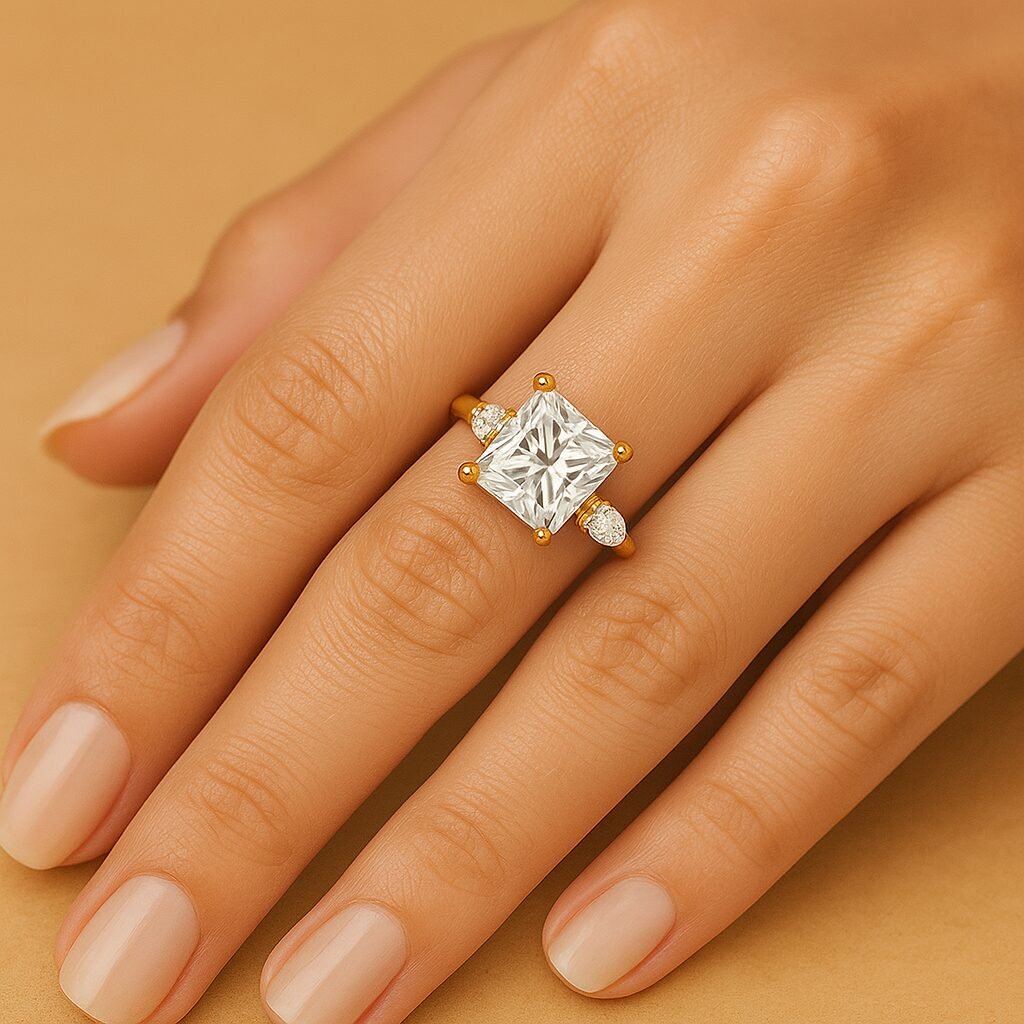UN1024 (1) Princess cut three-stone diamond ring in yellow gold with pear side stones, worn on woman's hand.