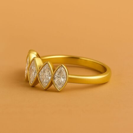Side angle of five-stone marquise diamond ring in yellow gold, bezel set in modern contoured design.