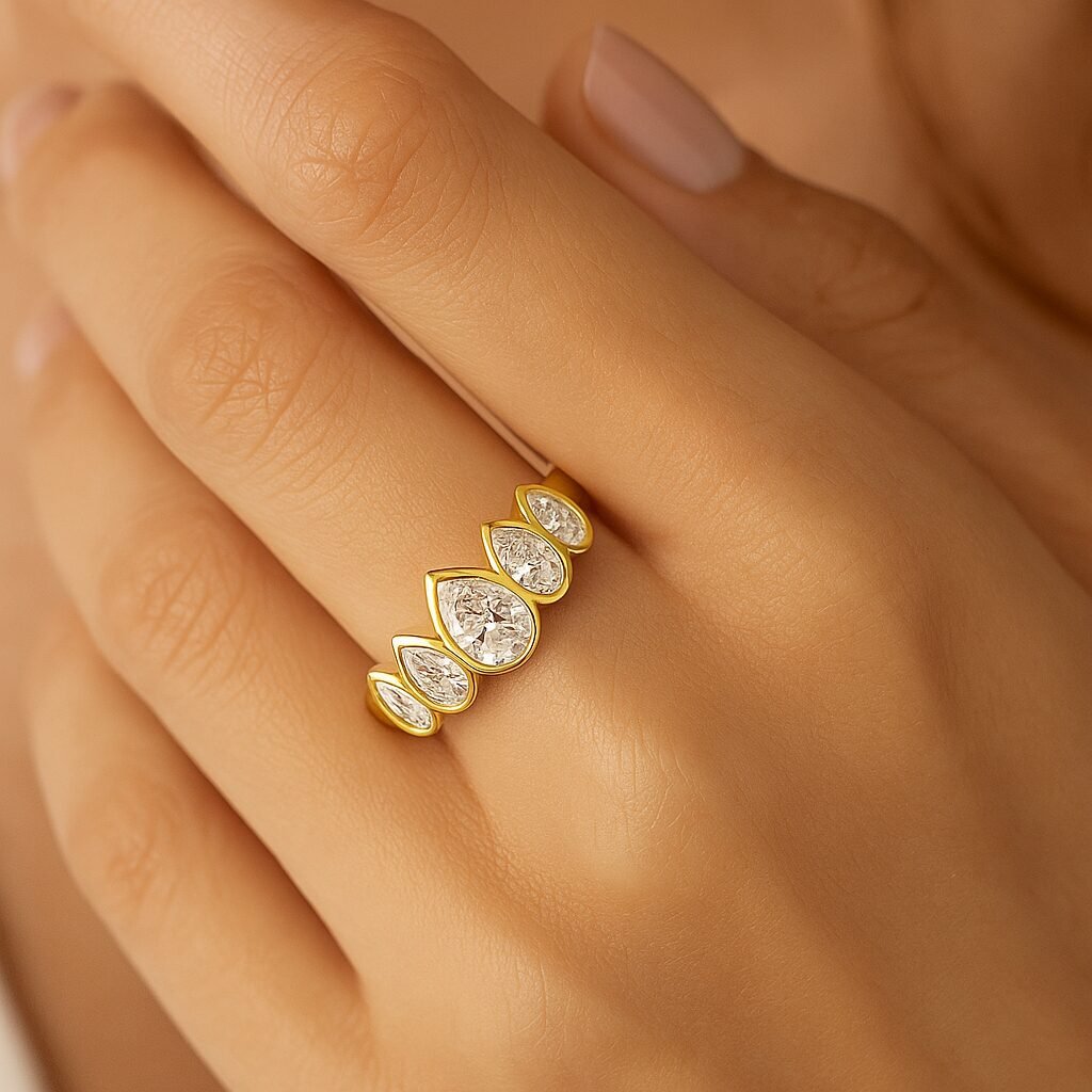 Elegant woman's hand wearing a five pear diamond ring in yellow gold with bezel setting, close-up perspective. Image 3 (Backside View)