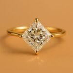 Front angle view of a princess cut solitaire engagement ring set in yellow gold.