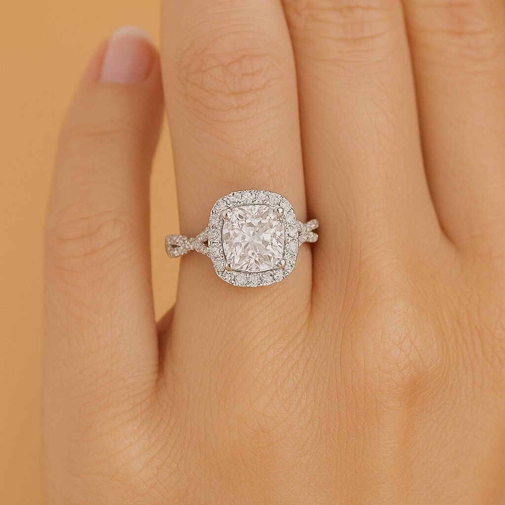 Cushion cut halo ring with twisted pavé band, worn on finger, emphasizing sparkle and elegance.