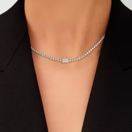 Woman wearing lab-grown diamond tennis necklace with center emerald-cut diamond accent – close-up neckline view